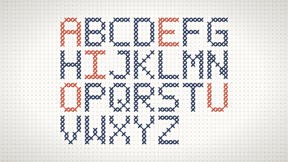Stitched block cross stitch alphabet from A to Z in navy with coral vowels on white Aida